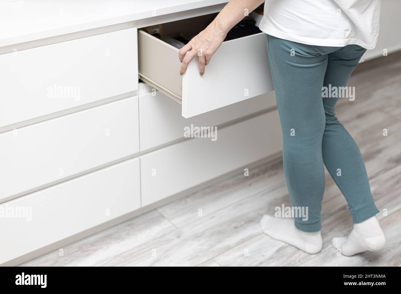 woman pulls out a drawer in a chest of drawers at home. High quality