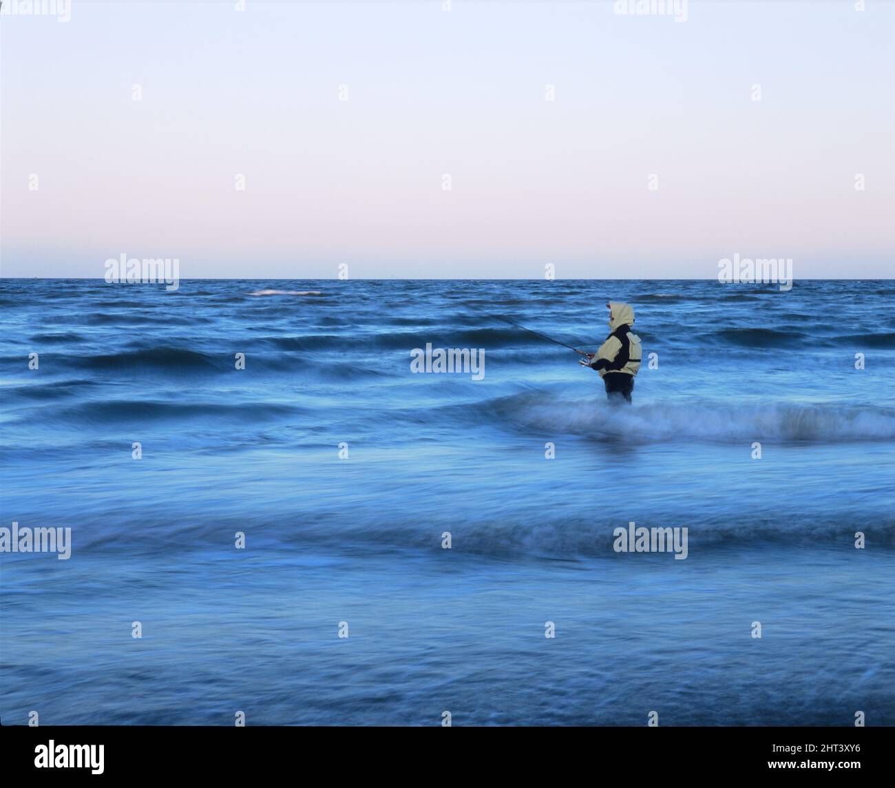 Woman fishing on the coast among waves Stock Photo