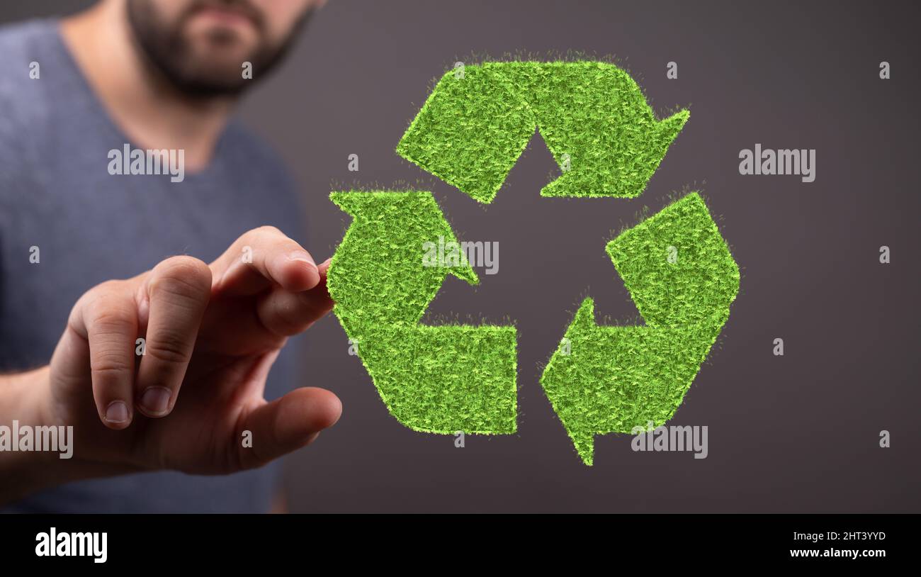 Close-up shot of 3d rendered volumetric green grass coated recycling sign in man's hand Stock Photo