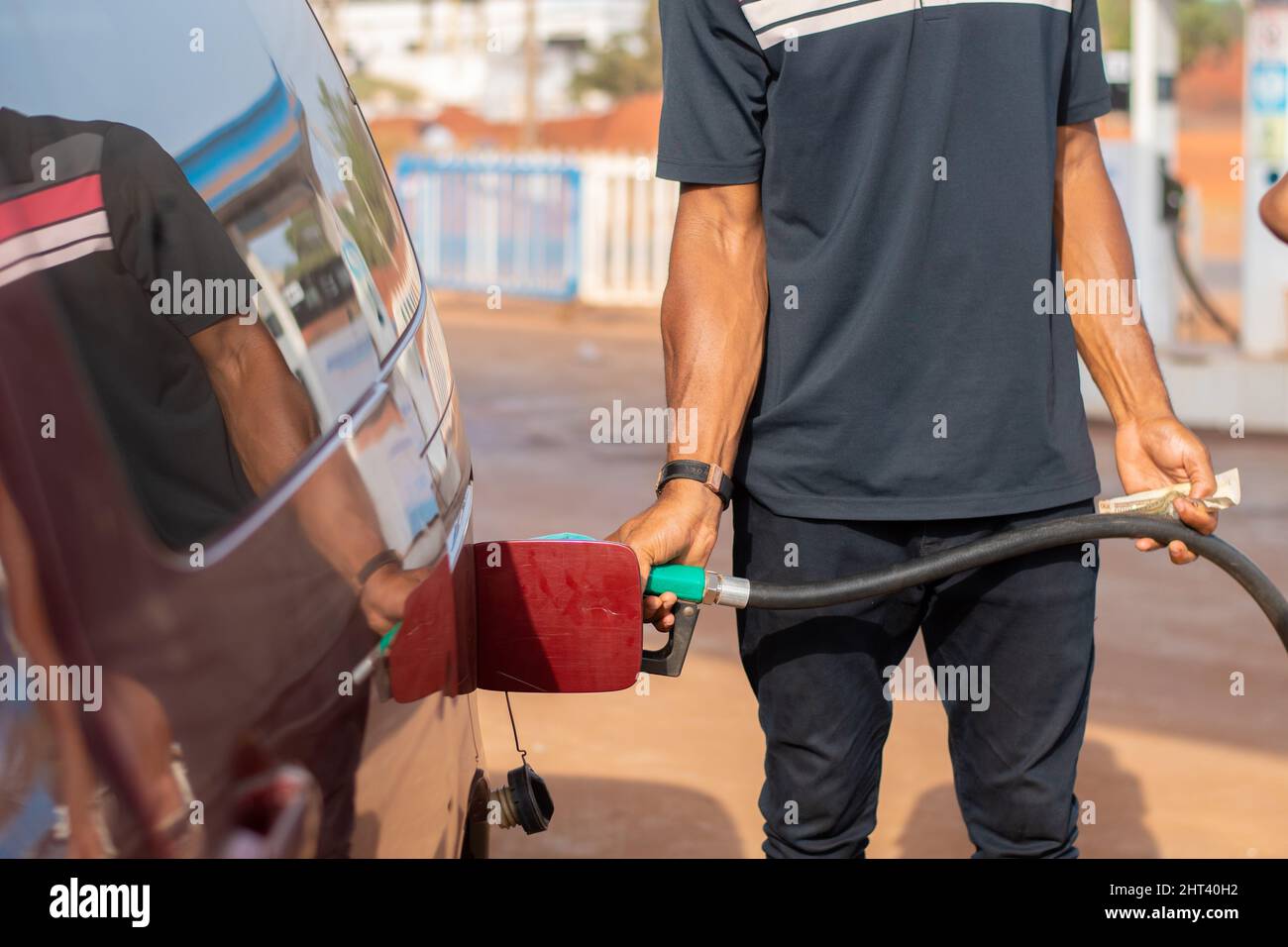 Nigerian man working as a petrol station attendant filling up a car ...