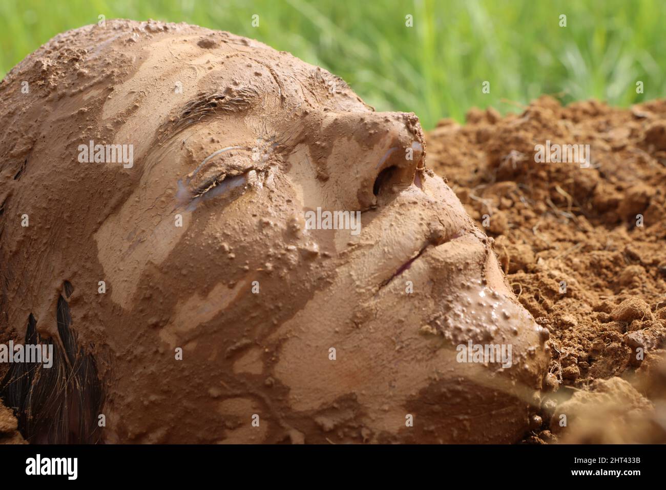 A woman buried in the ground A face covered in the ground Stock Photo