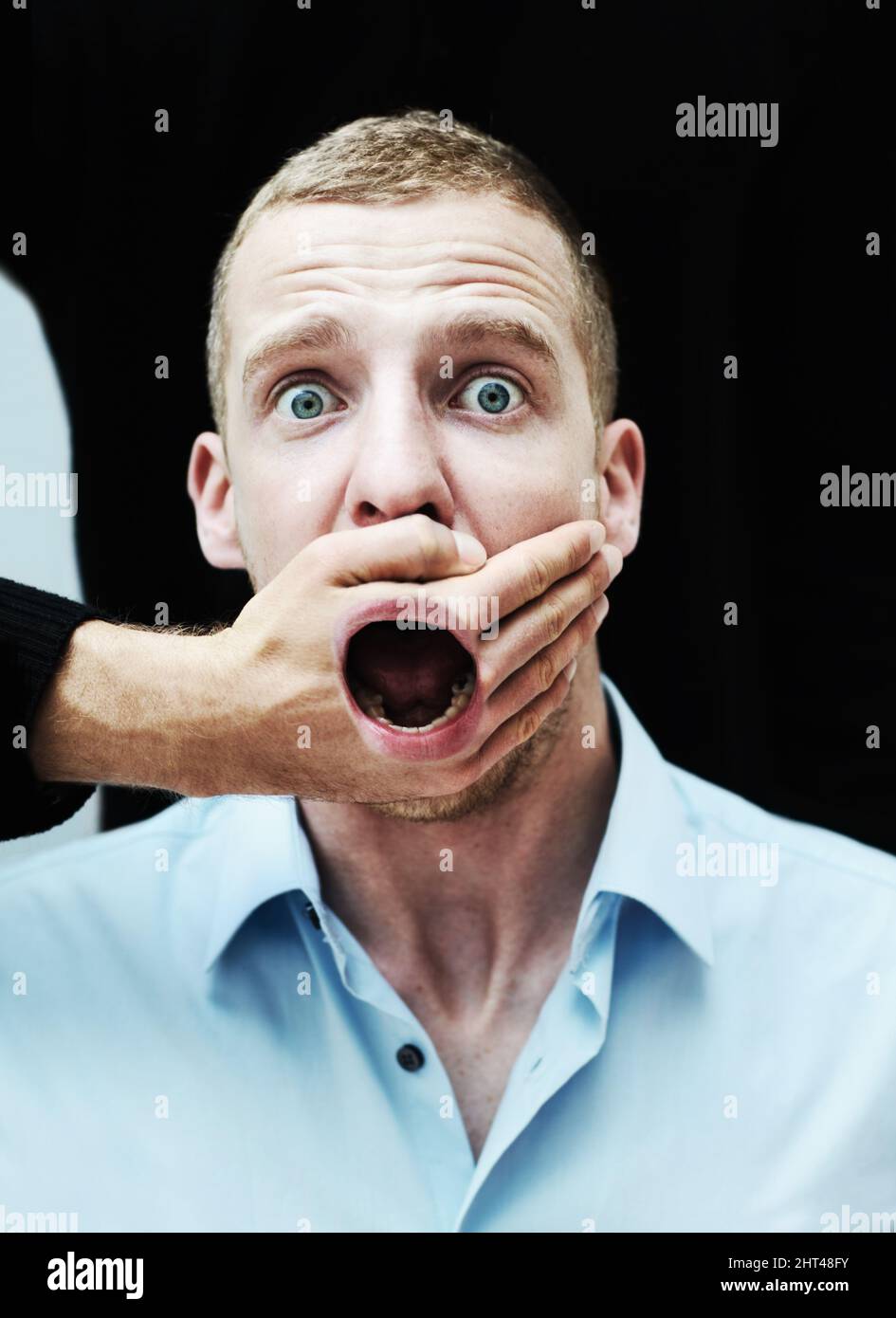 I will not be silenced. A distraught looking man with his mouth showing through the hand trying to silence him. Stock Photo
