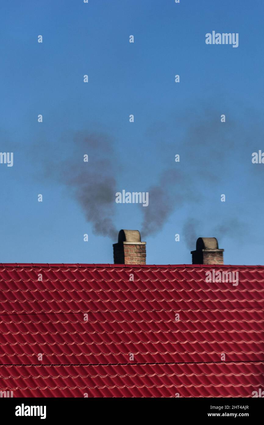 Vertical shot of smoke coming out of the chimneys on a red roof Stock Photo
