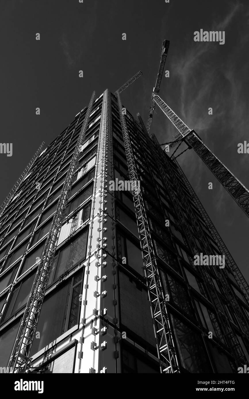 Grayscale of a modern high-rise building in the shell with construction crane in Frankfurt am Main Stock Photo