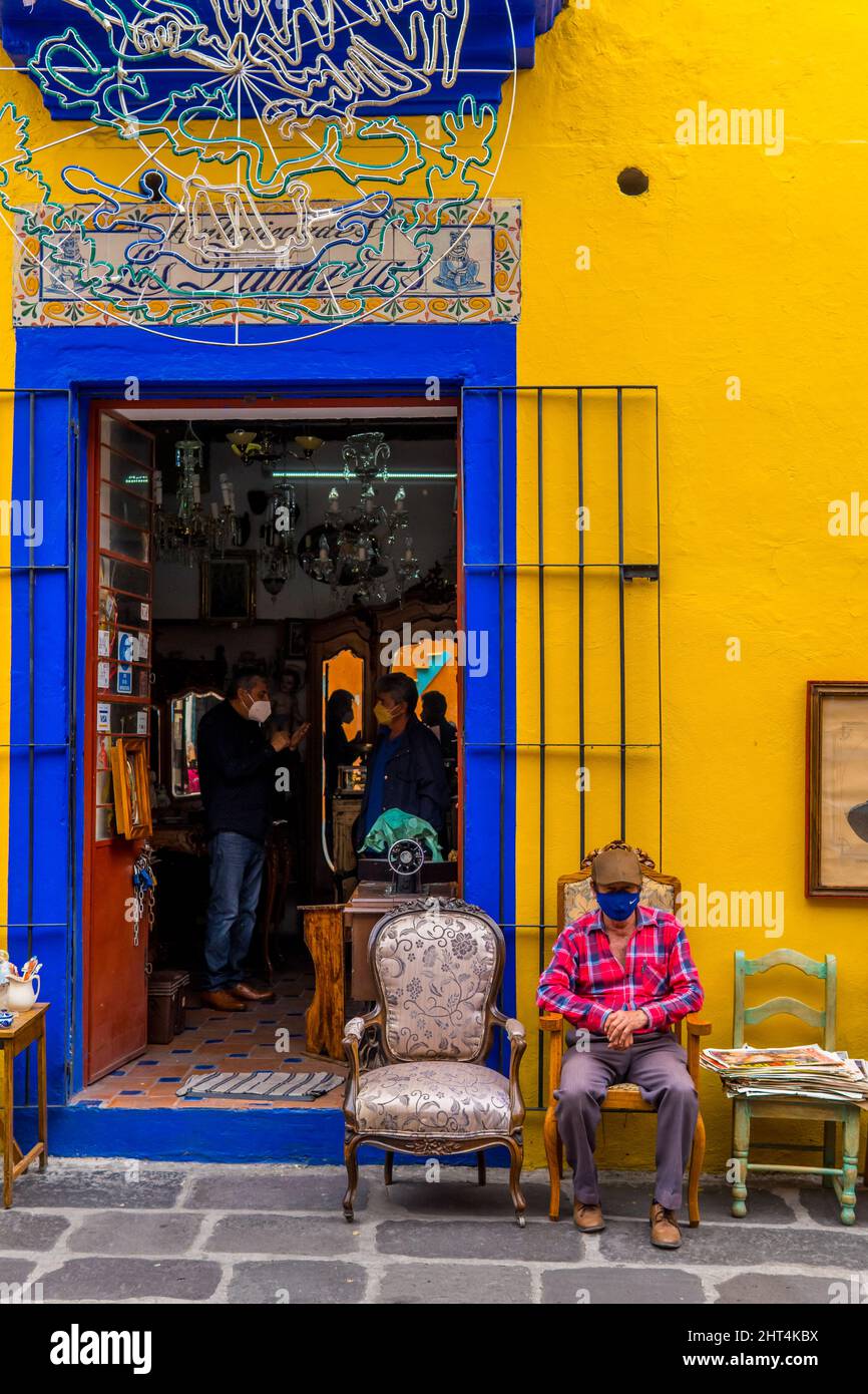 View of man sitting in front of antiques shop in Los Sapos market Stock ...