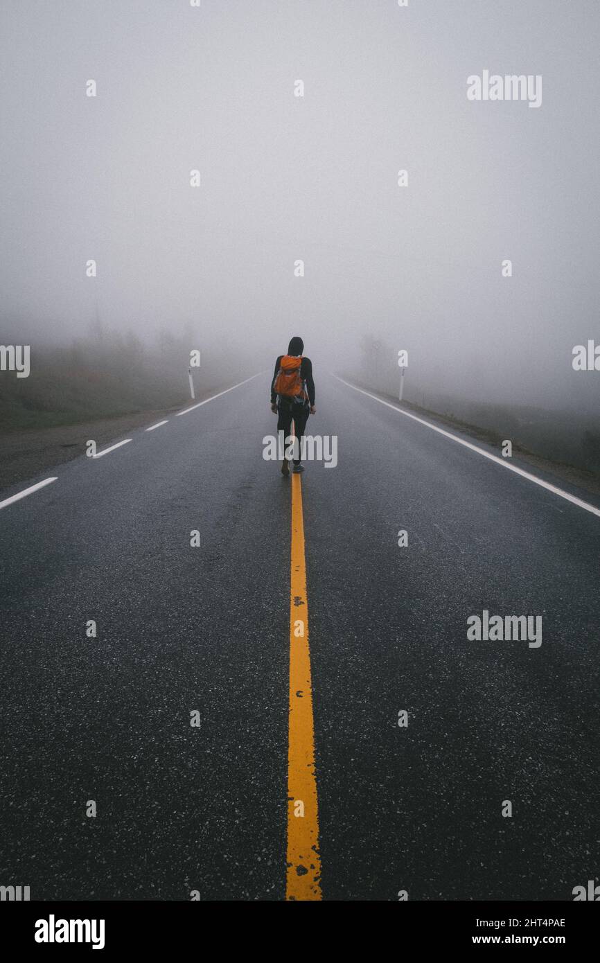 Lonely man walking on foggy road hi-res stock photography and images ...