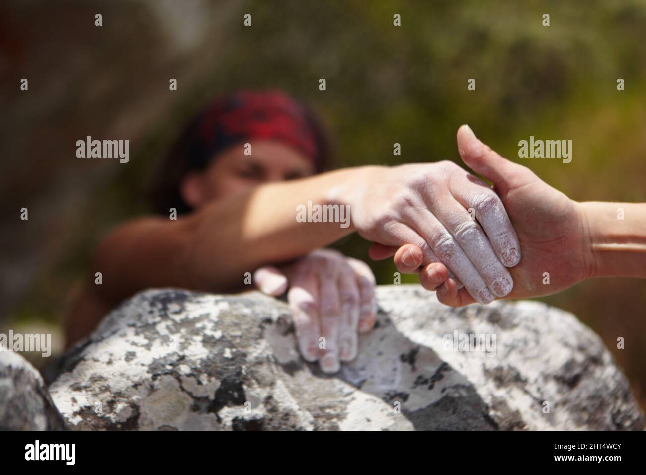 A helping hand. One rock climber giving a helping hand to another Stock ...
