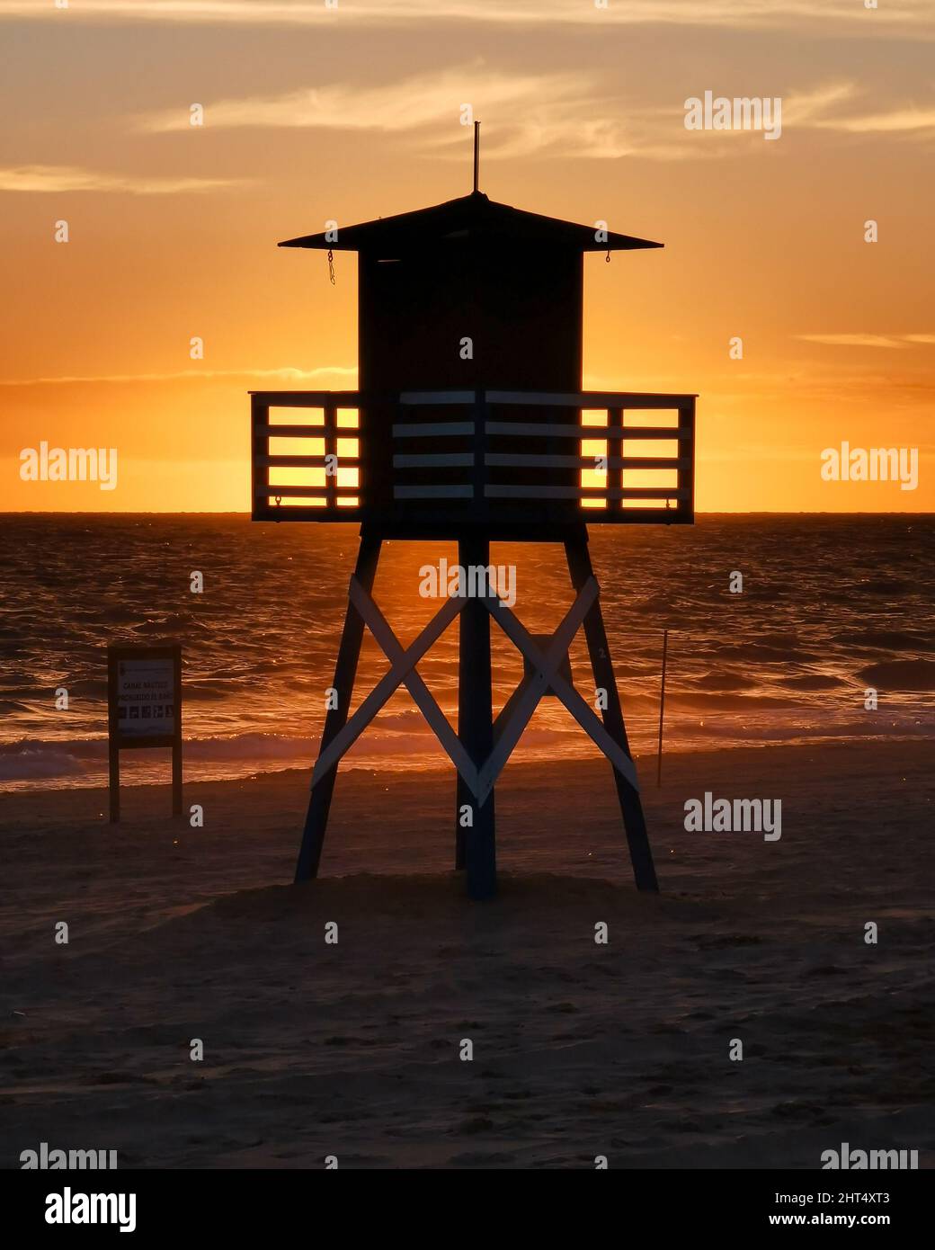 A beautiful portrait of the silhouette of a lifeguard house facing the sunset on the beach Stock Photo