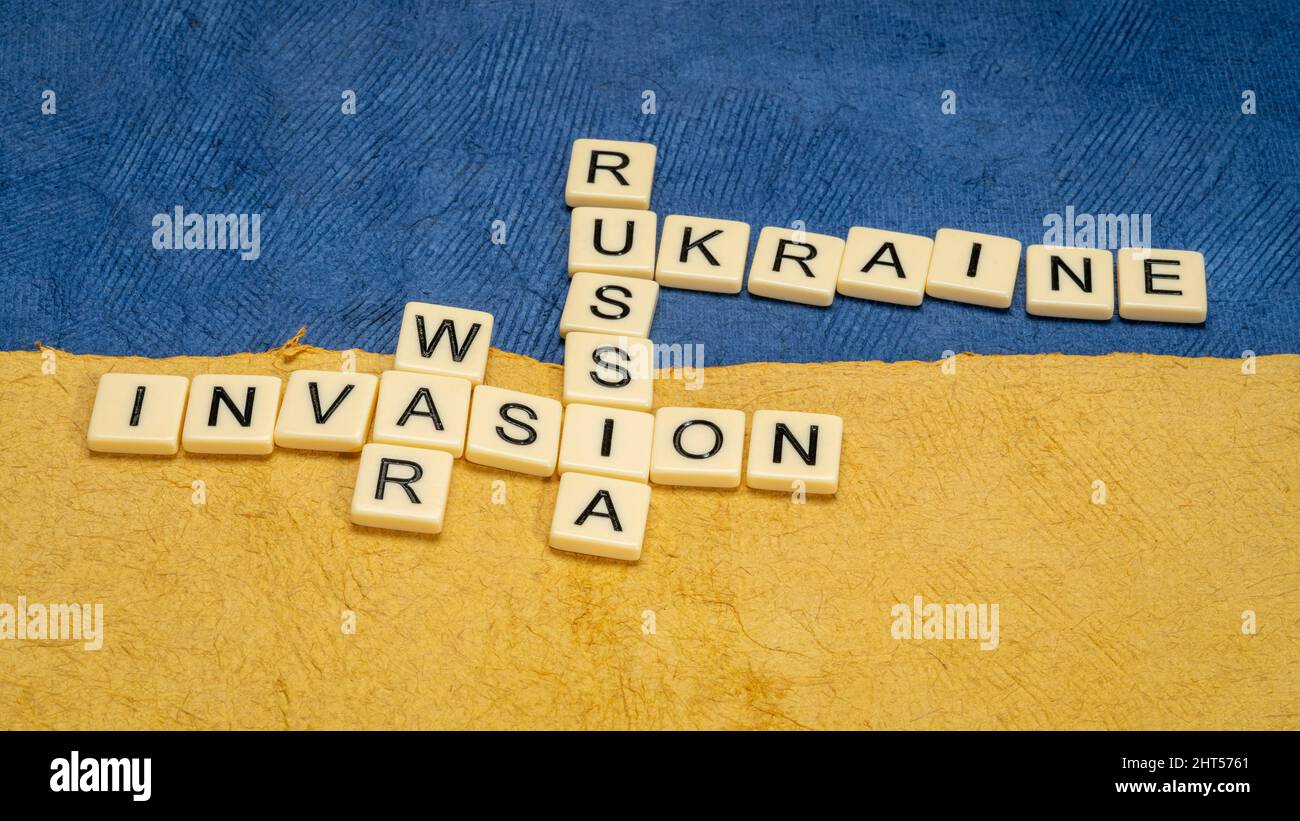 Ukraine, Russia, war and invasion crossword in ivory letter tiles against paper abstract in colors of Ukrainian national flag, blue and yellow Stock Photo