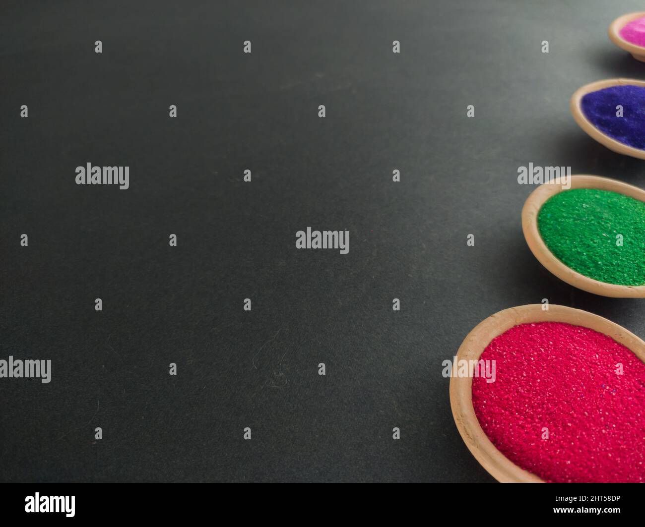 colorful powders for holi on clay pots on occasion of indian festival of colors. happy holi theme shot against black background. copy space for text. Stock Photo