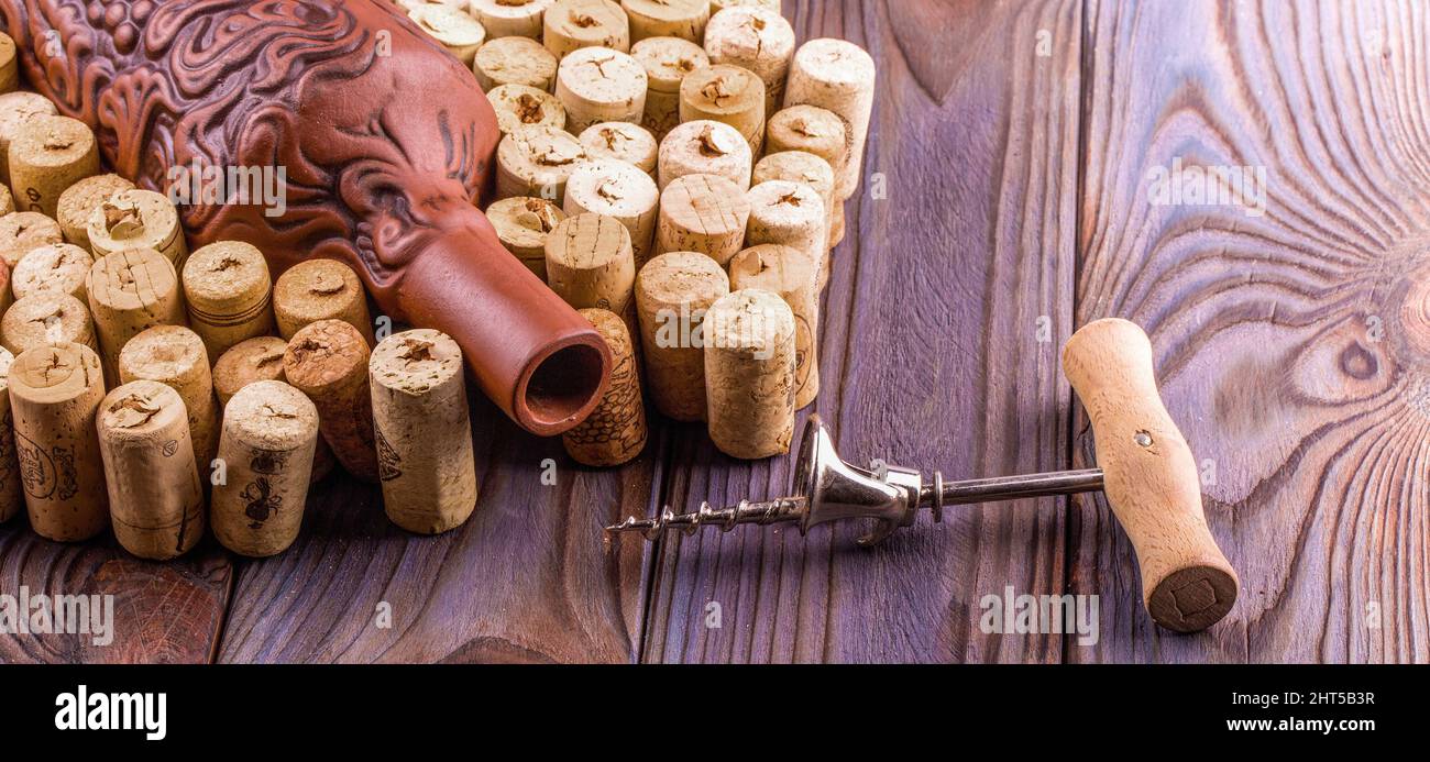 Clay bottle, metal corkscrew and cork on a wooden table. Stock Photo