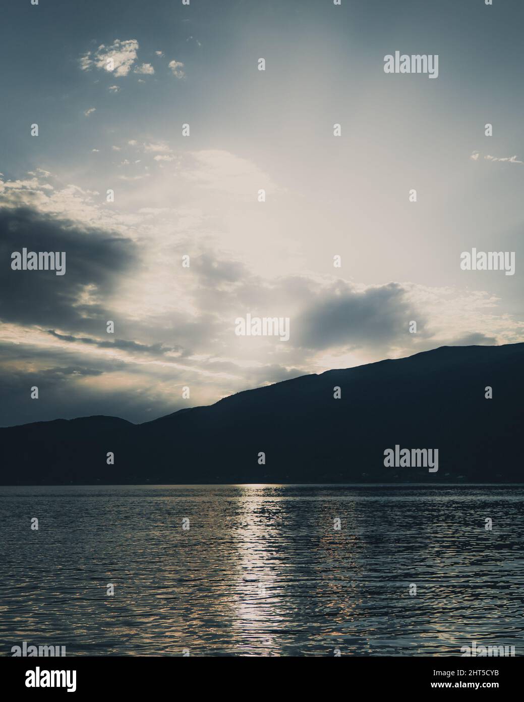 Vertical shot of the silhouette of a mountain and a lake with ...