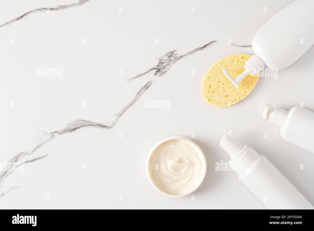 Facial cleanser, face wash product bottles with face cleansing sponge on marble background. Top view, flat lay. Copy space Stock Photo