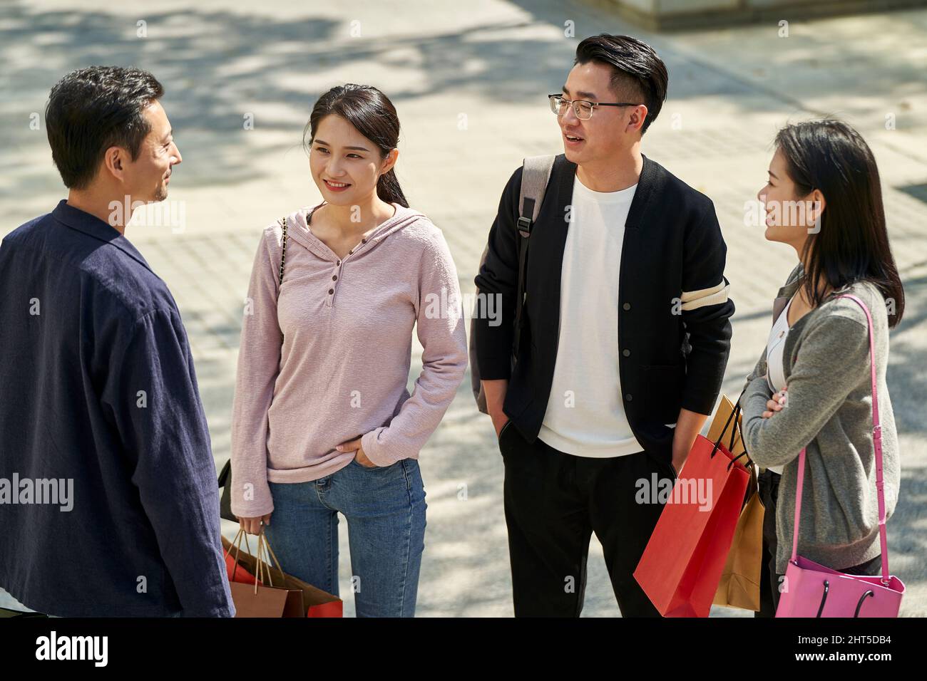 young asian people standing talking on street happy and smiling Stock Photo