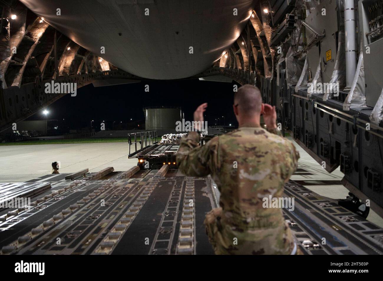 February 24, 2022 - Travis Air Force Base, California, USA: U.S. Air Force Airman 1st Class Chase Smith, 8th Airlift Squadron loadmaster, marshals a K-loader toward a C-17 Globemaster III assigned to Joint Base Lewis-McChord, Washington, at Travis Air Force Base, California, Feb. 14, 2022. U.S. Airmen with the 60th Aerial Port Squadron and 8th Airlift Squadron loaded cargo to the C-17. K-loaders are used to transport cargo into and out of aircraft. Under the direction of U.S. Under the direction of U.S. Transportation Command, the 60th Air Mobility Wing supported the 621st Contingency Respons Stock Photo
