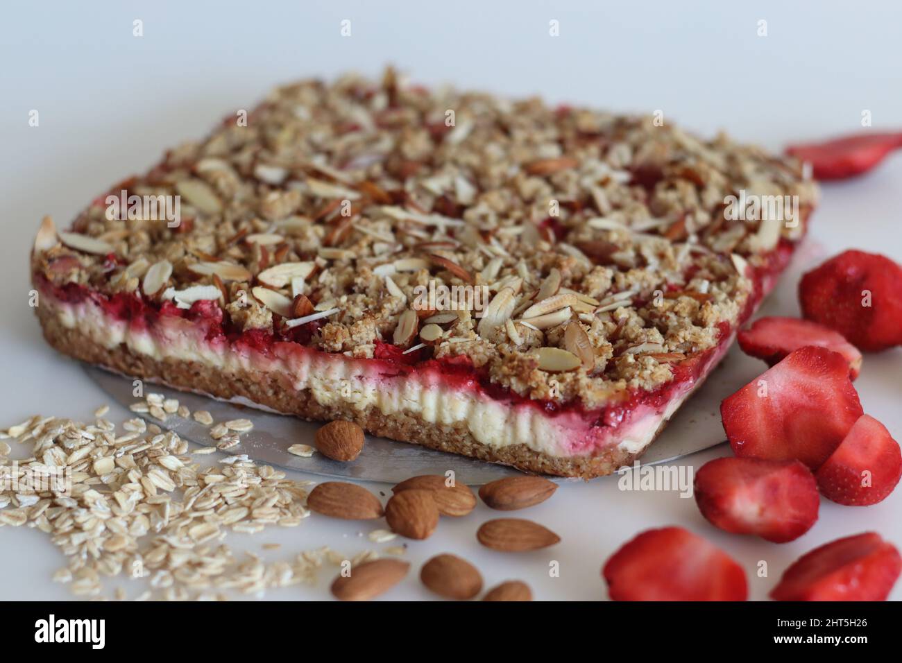 Breakfast bar, fresh from oven taken out of mould. No flour breakfast bar with rolled oats, almonds, cream cheese and fresh strawberries. Shot on whit Stock Photo