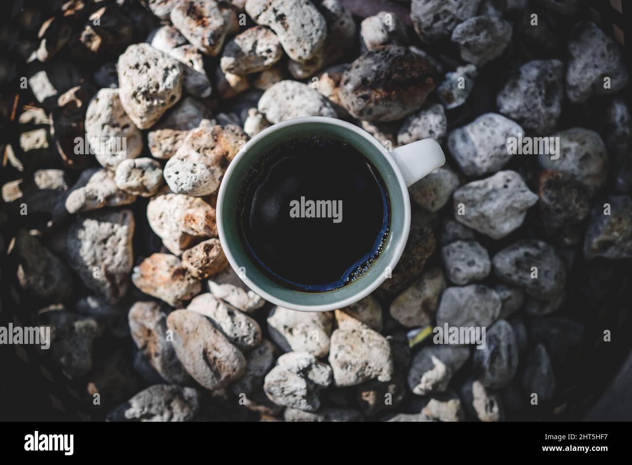 Top view of the cup of black coffee on the rocks in the morning Stock