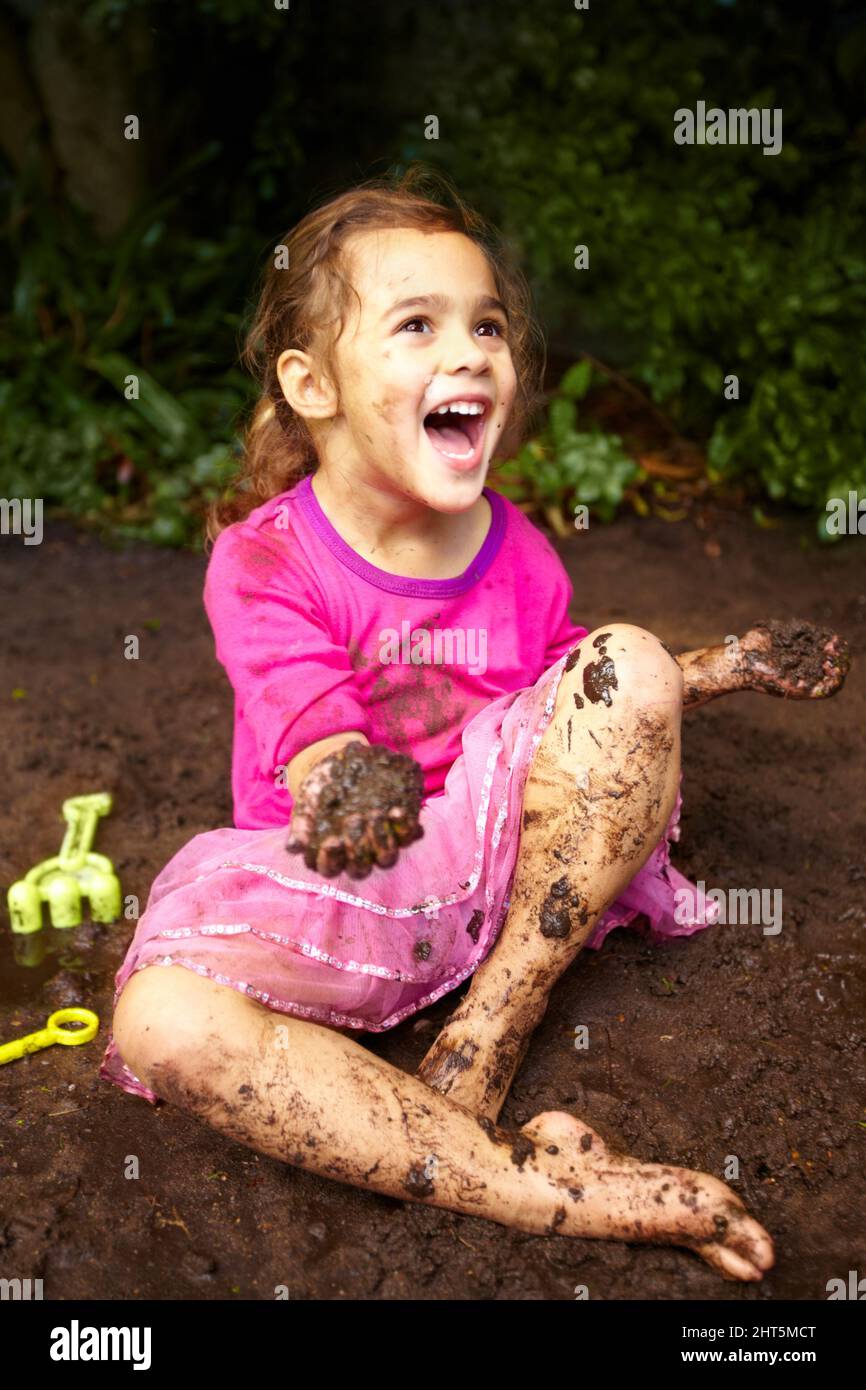 Childhood is all about getting dirty. Shot of a little girl playing outside in the mud Stock