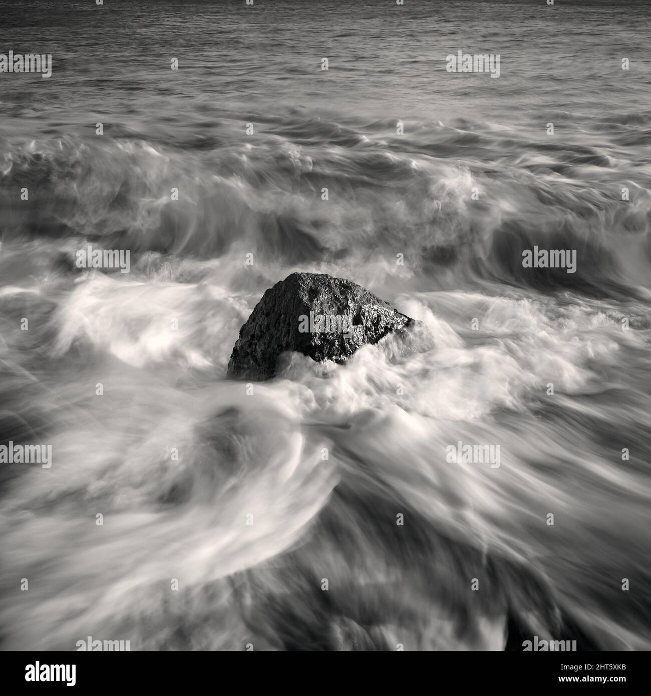 Grayscale shot of sea waves crashing on a rock at the beach Stock Photo ...