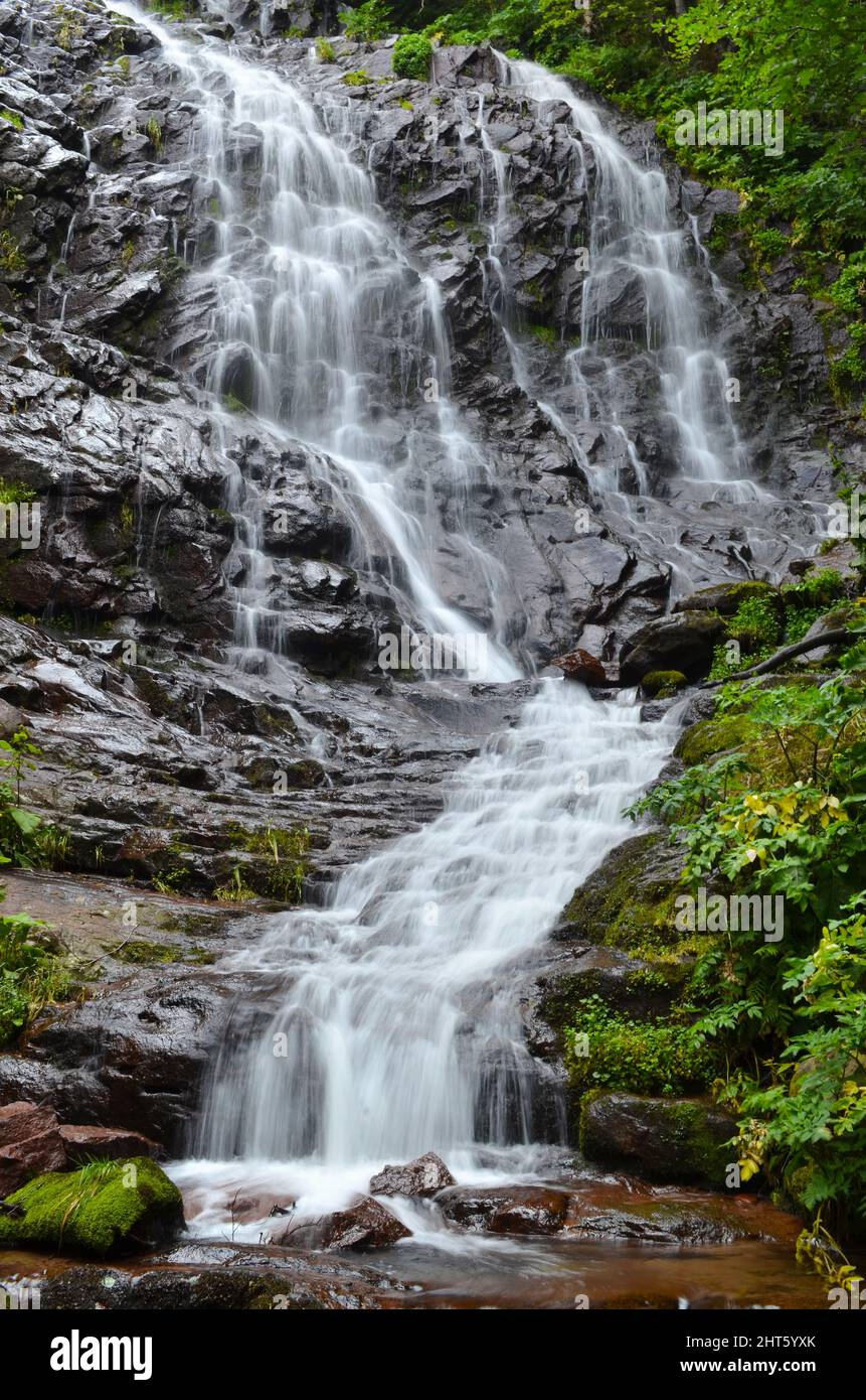 Vertical shot of a beautiful waterfall streaming down into the rocks ...