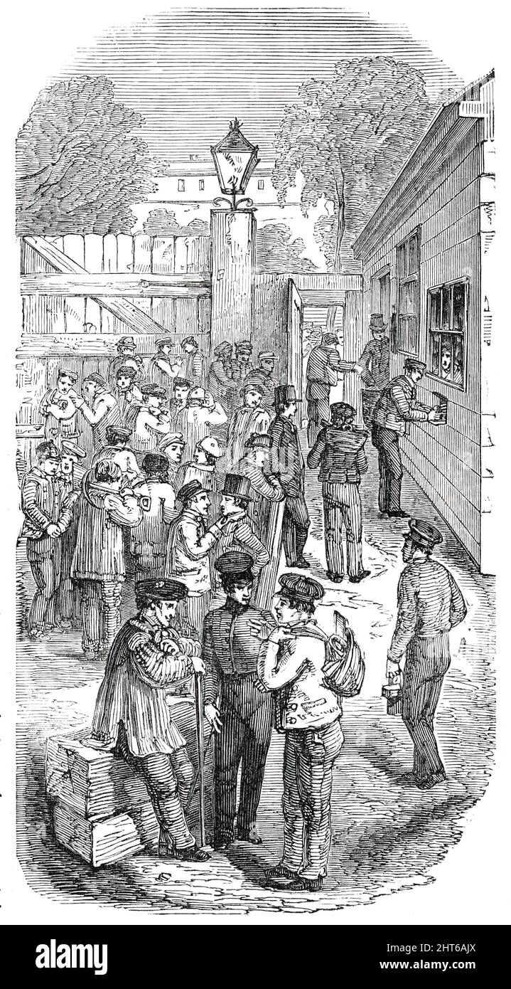 Great Exhibition Building - Paying the Workmen, 1850. '...the exterior of the pay-office is seen on the right, with a workman in the act of taking from the box his weekly wages, contained in a small open cylinder of zinc, together with a slip of paper, having his name, his number, and the exact amount due to him written thereon....At the exit gate...is stationed a policeman, whose duty it is to see that each man, as he passes from the pay-box to the exit gate, casts the zinc box into a large basket...Now, with a view to prevent confusion, separate gangs of men...are called up...among so large Stock Photo