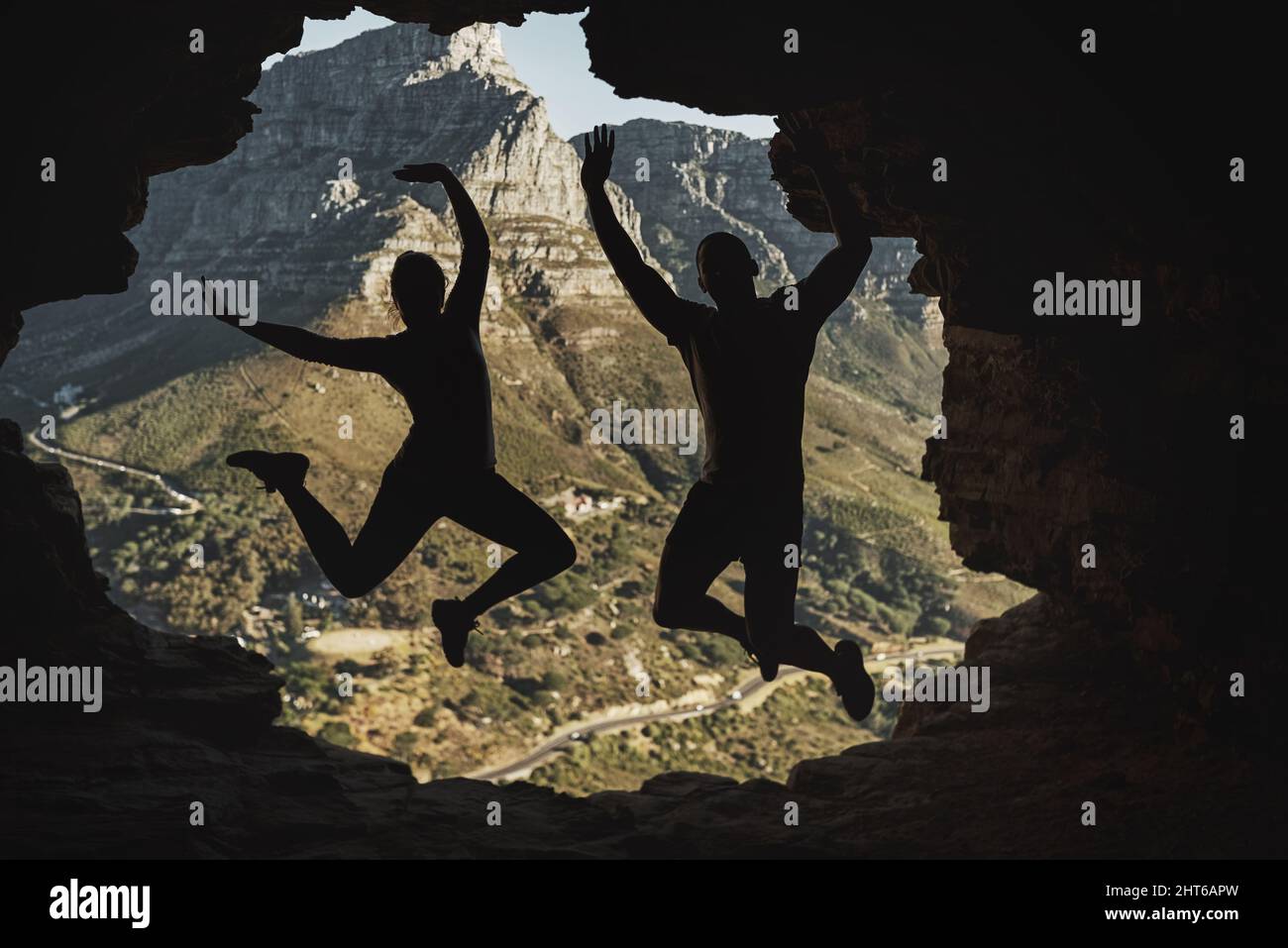 We did it. Rearview shot of a young couple jumping in excitement while hiking in the mountains. Stock Photo