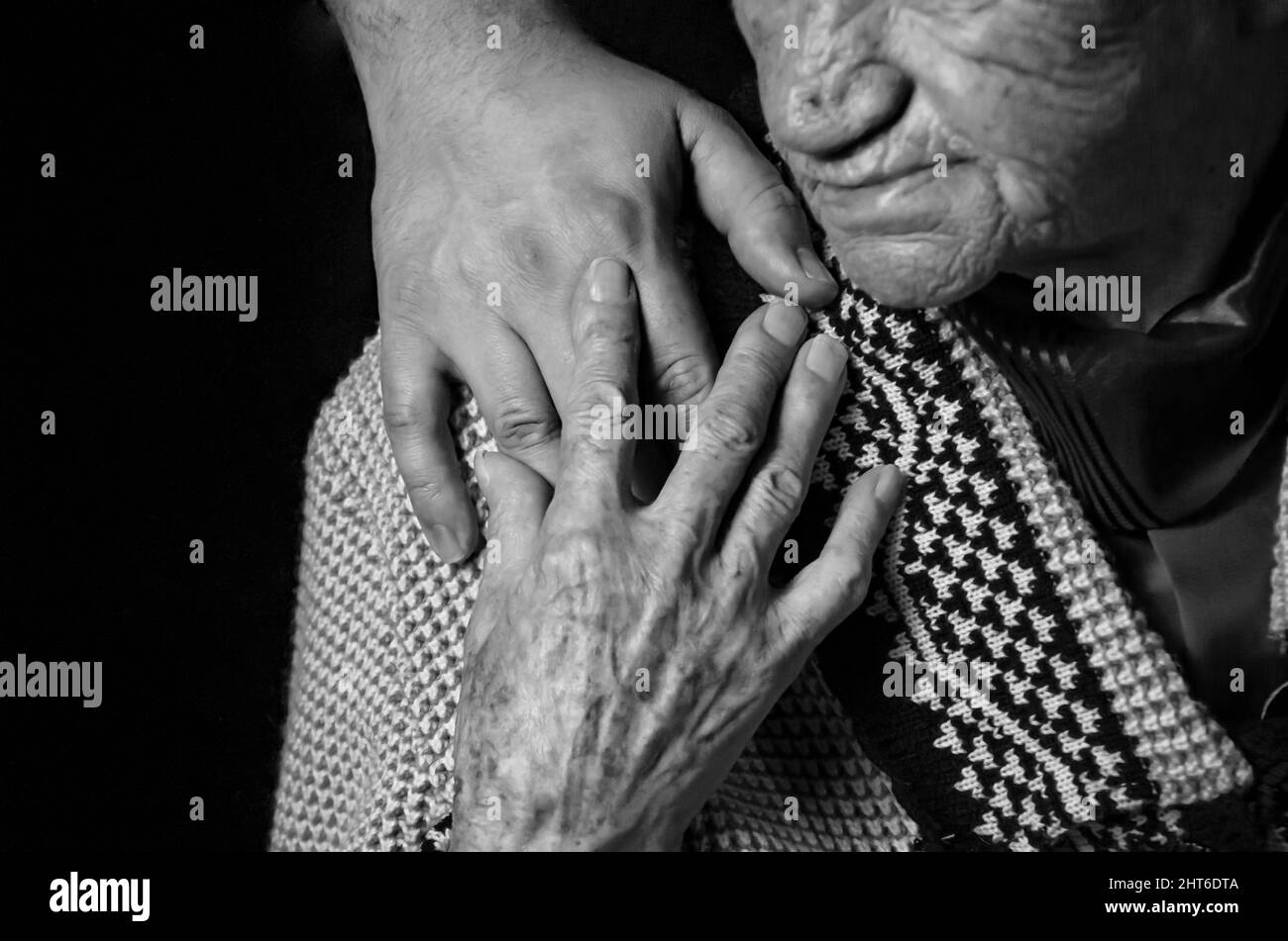 Hands of an elderly woman against black background. black and white photo. Stock Photo