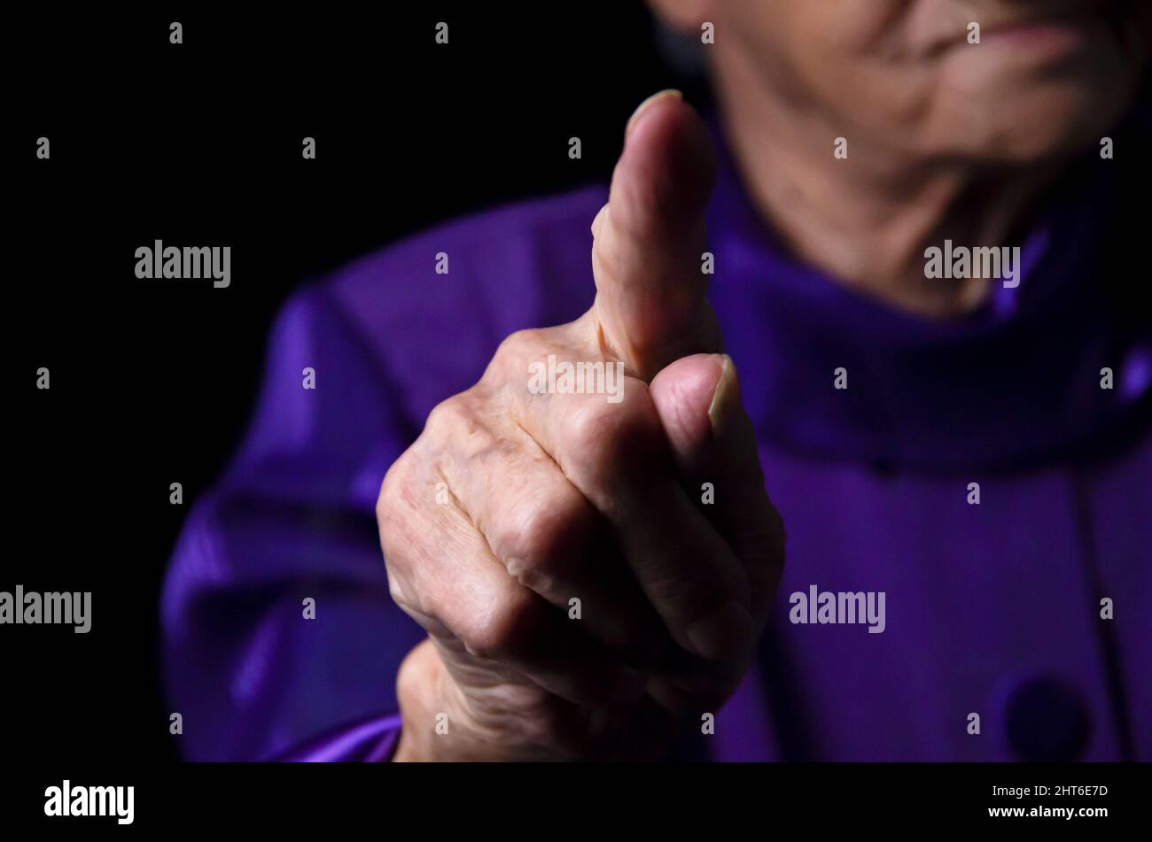 Elderly lady is shaking her fingera black background. Stock Photo