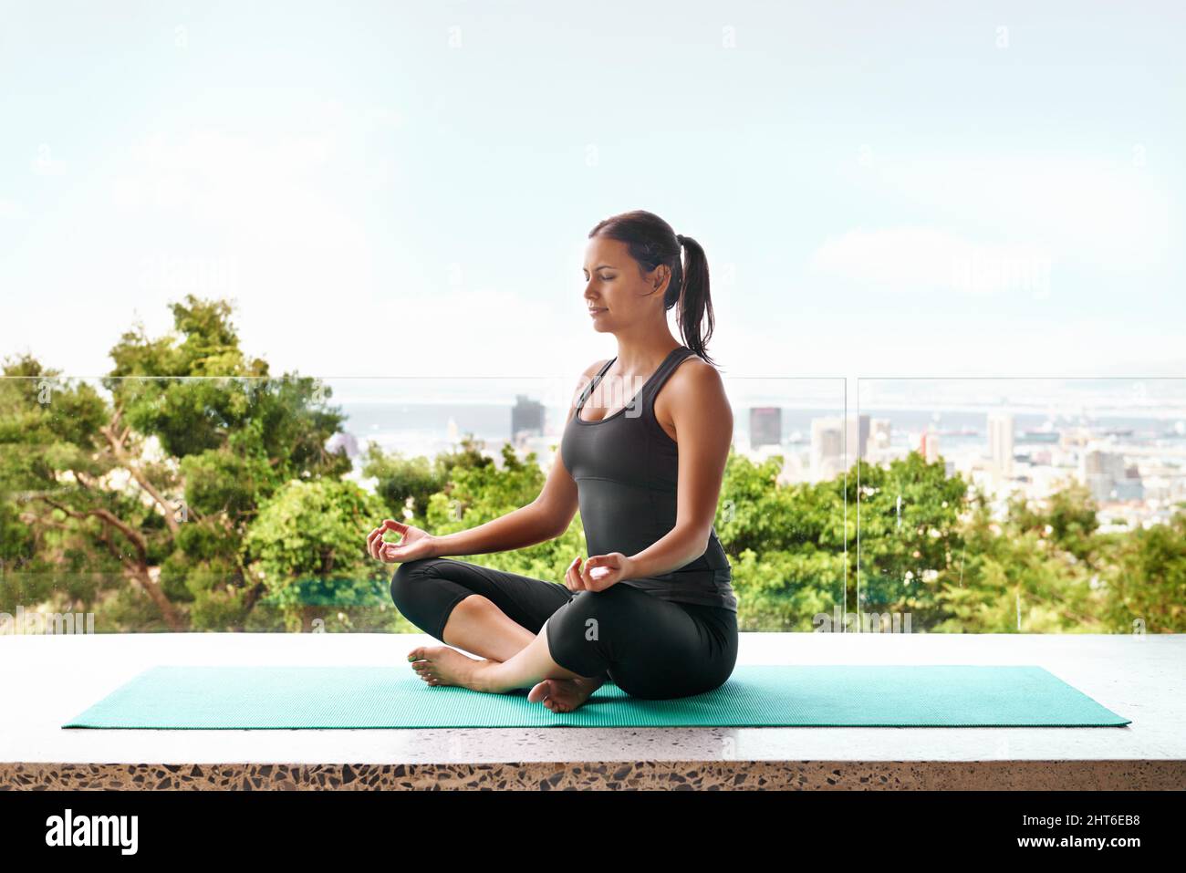 Overall wellbeing.... Full-length shot of a sporty young woman doing yoga on a balcony. Stock Photo