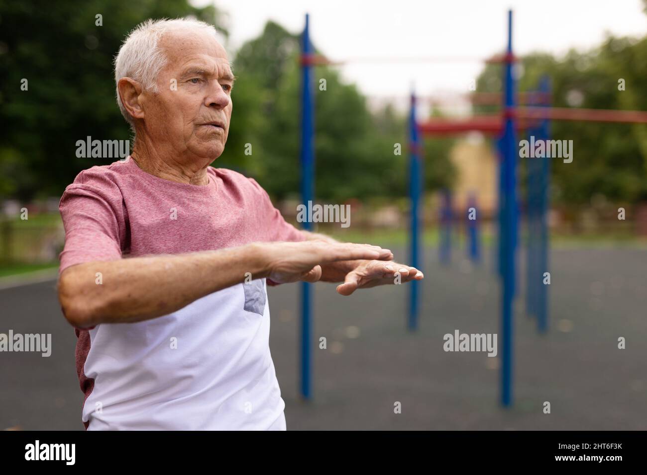 Elderly man doing fitness exercises outdoors Stock Photo