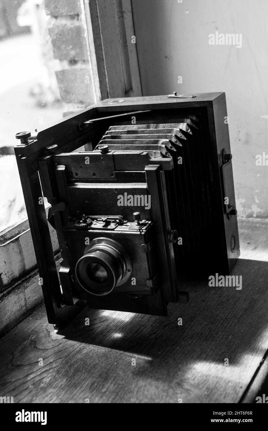 Vertical grayscale shot of a vintage camera on a windowsill Stock Photo