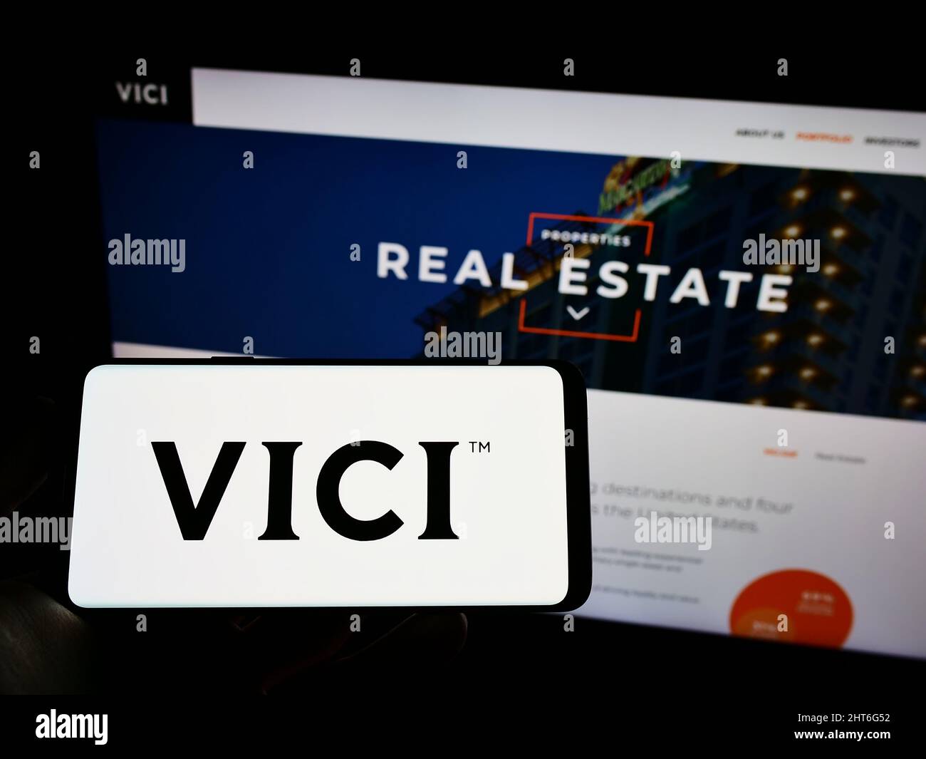 Person holding mobile phone with logo of American real estate company Vici Properties Inc. on screen in front of web page. Focus on phone display. Stock Photo