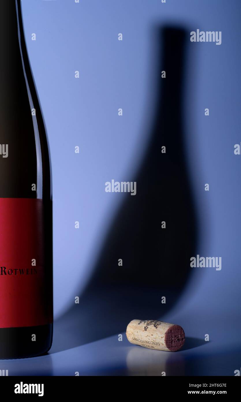 Red wine bottle and plug casting shadow on blue backround Stock Photo