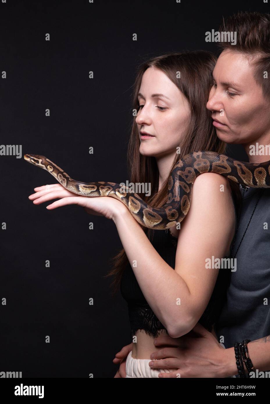 Photo of two hugging women with python on shoulders Stock Photo