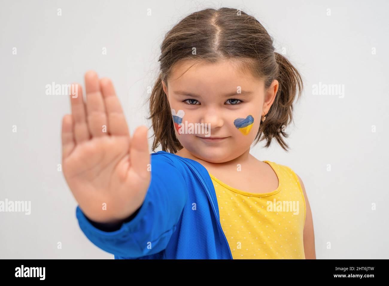 Child with ukraine and russia colors shows hand stop war Stock Photo