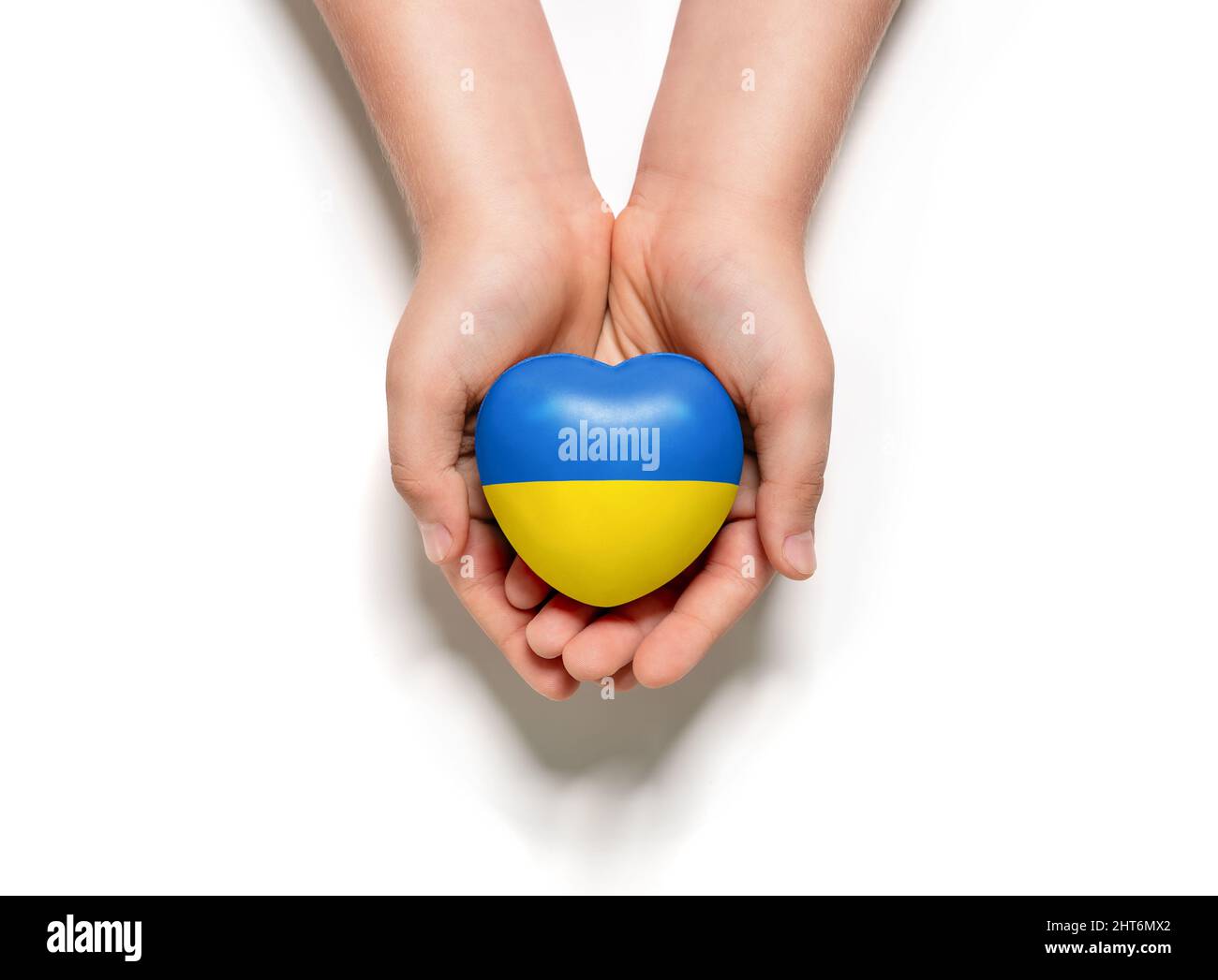 High angle view of child hands holding ukraine flag painted heart isolated on white background Stock Photo