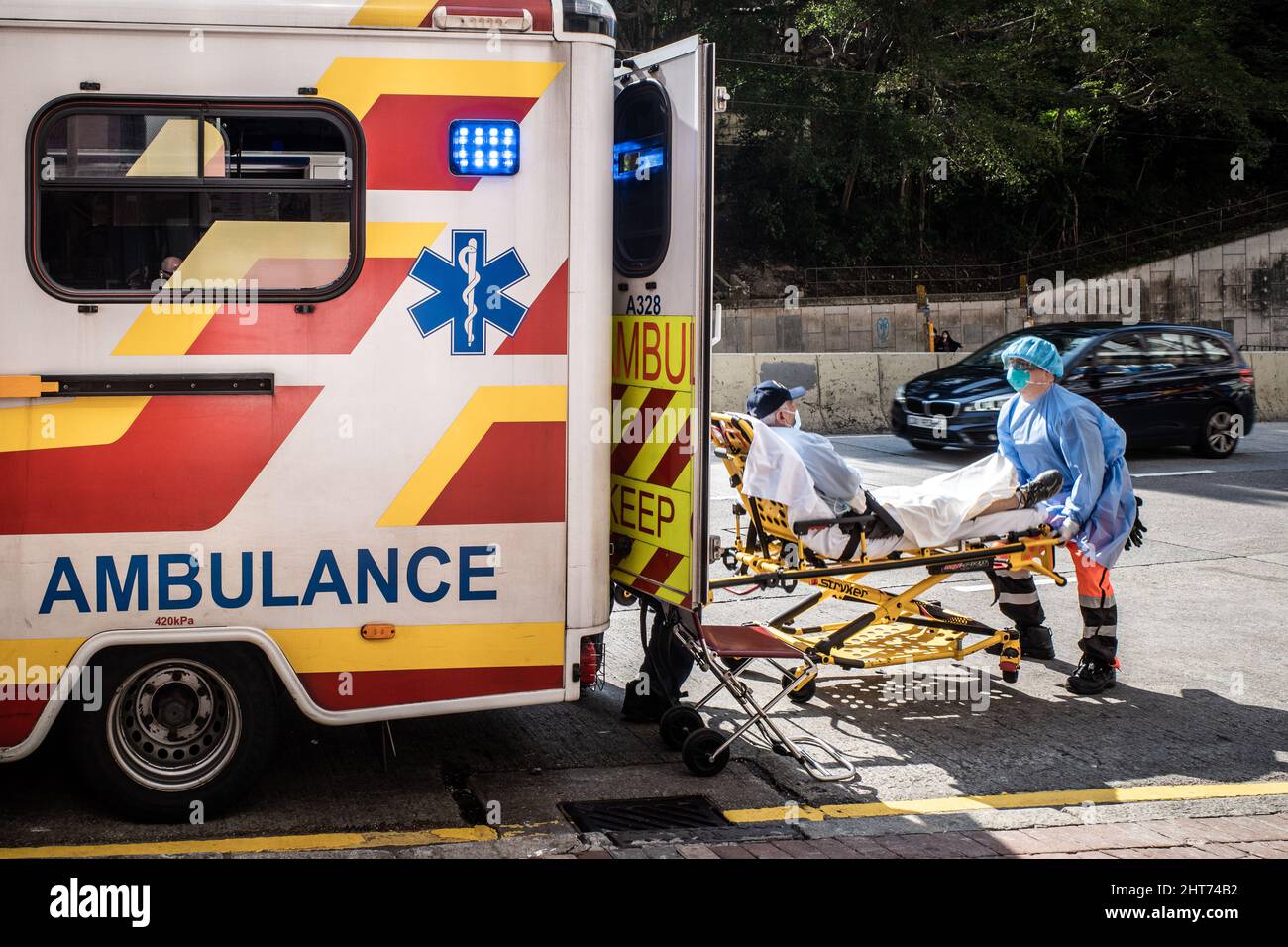 Hong Kong, China. 27th Feb, 2022. Paramedics in Hong Kong put a patient in  an ambulance. Demand has soared due to the COVID-19 pandemic and some  medical workers have tested positive or