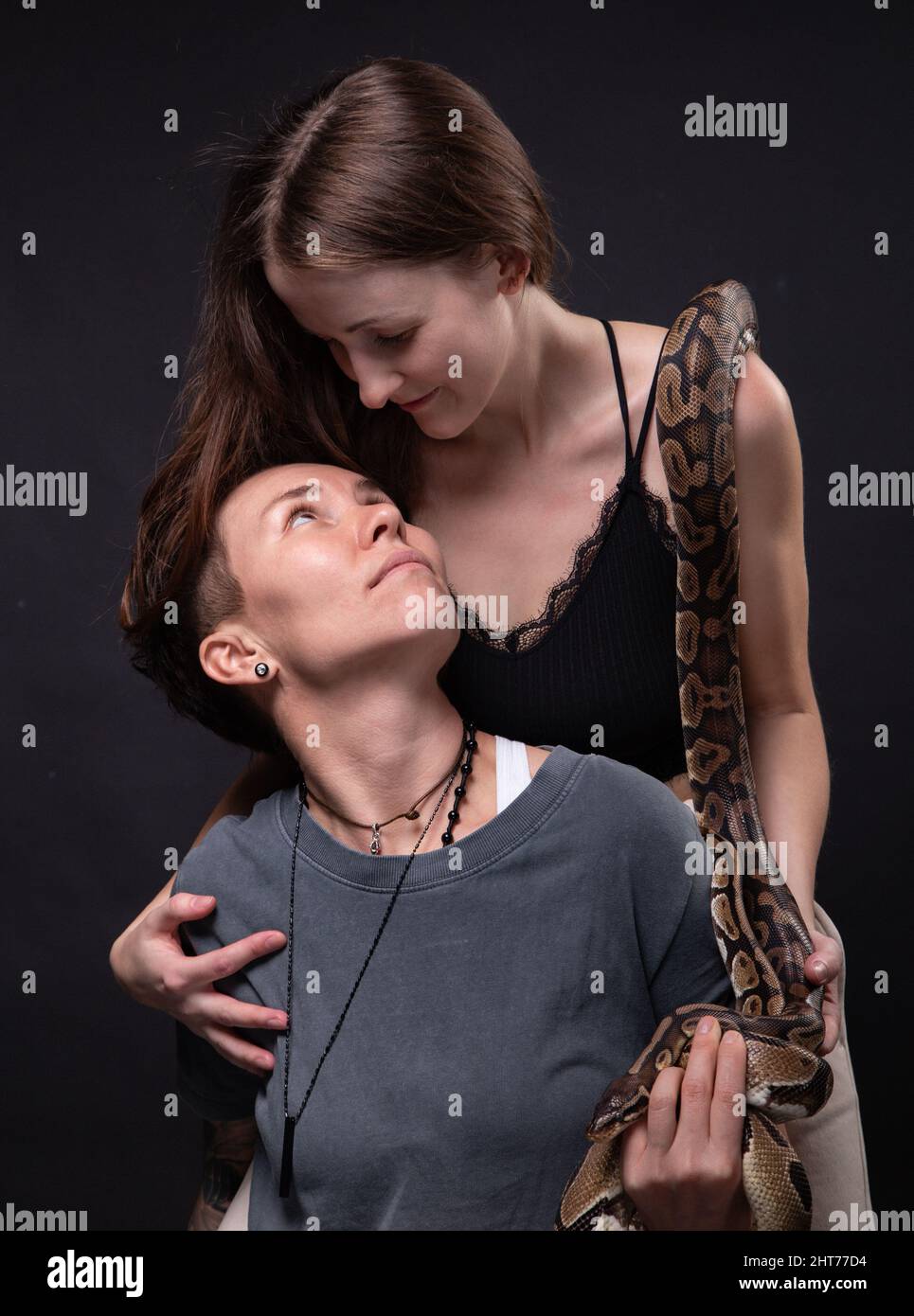 Photo of two hugging women with snake on shoulders Stock Photo