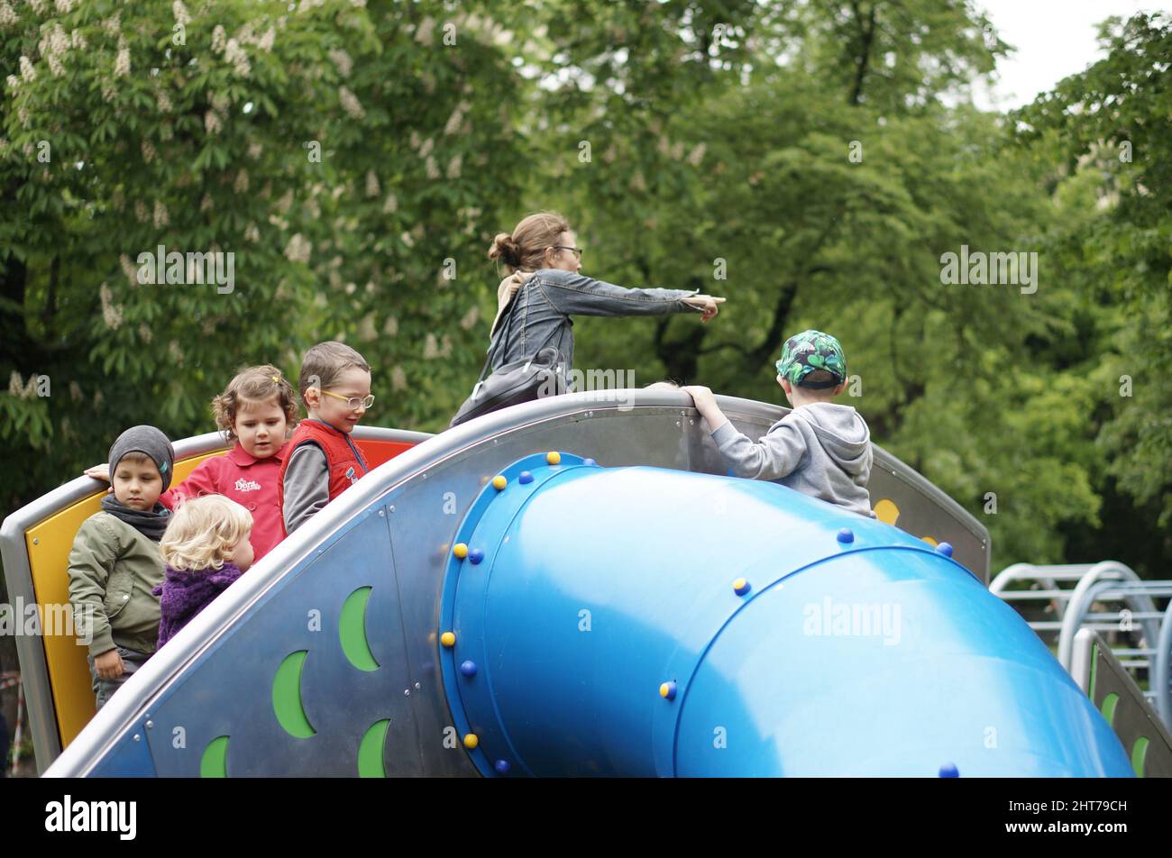 Group of children playing near a slide on a playground in the Stary Browar park in Poland Stock Photo