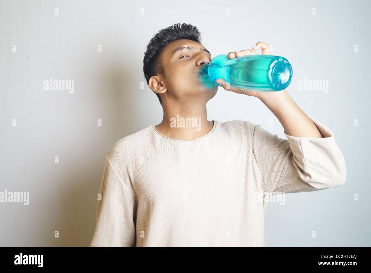Young man drinking from a blue water bottle Stock Photo