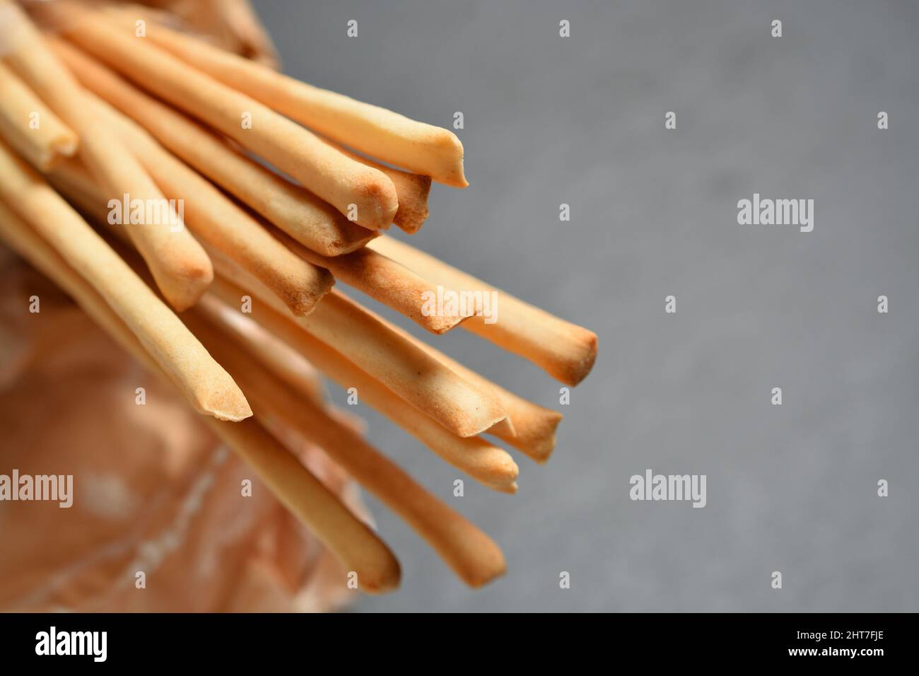 Thin breadsticks called Grissini Torinesi. Shallow depth of field. Grey neutral background for