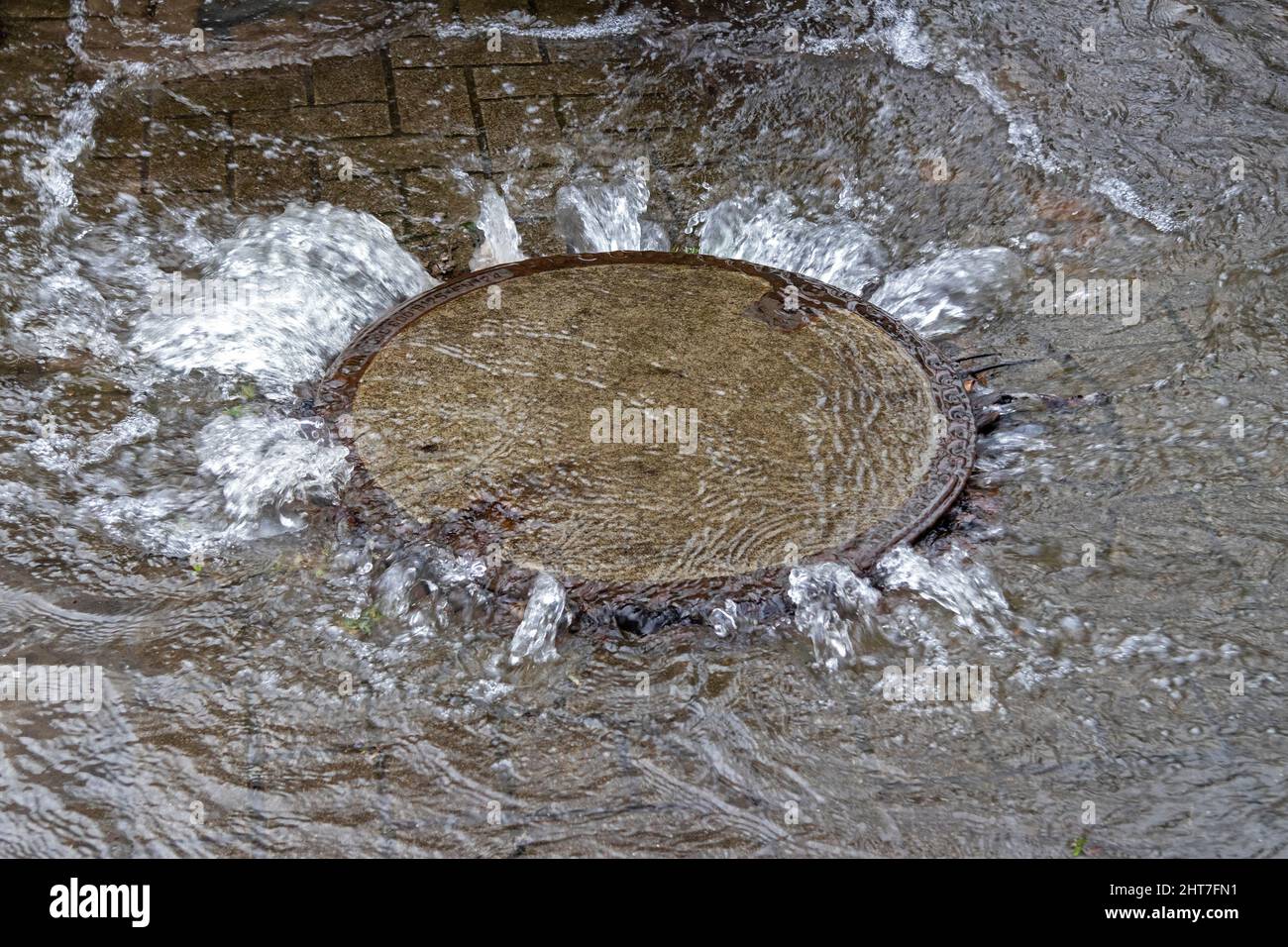 Water emerging from a manhole cover, Wilhelmsburg, Hamburg, Germany Stock Photo