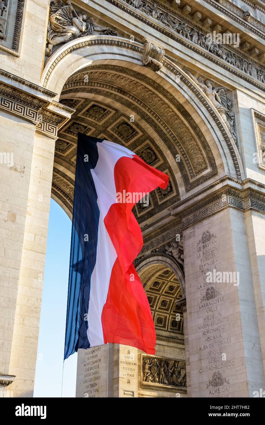 A large french flag is fluttering in the wind under the vault of the Arc de Triomphe in Paris, France. Stock Photo