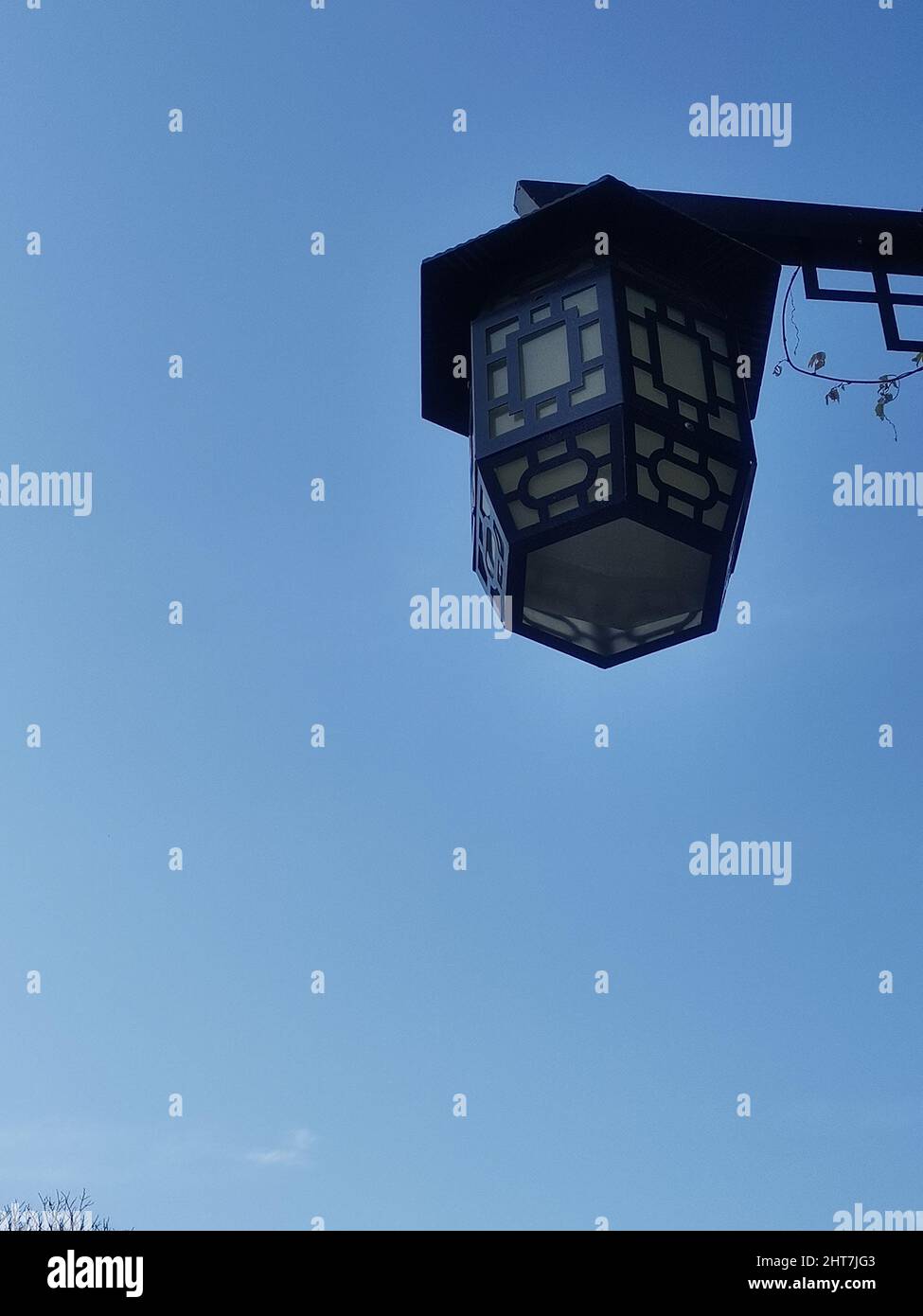Vertical shot of a street light with black metal ornaments on the background of the blue sky Stock Photo