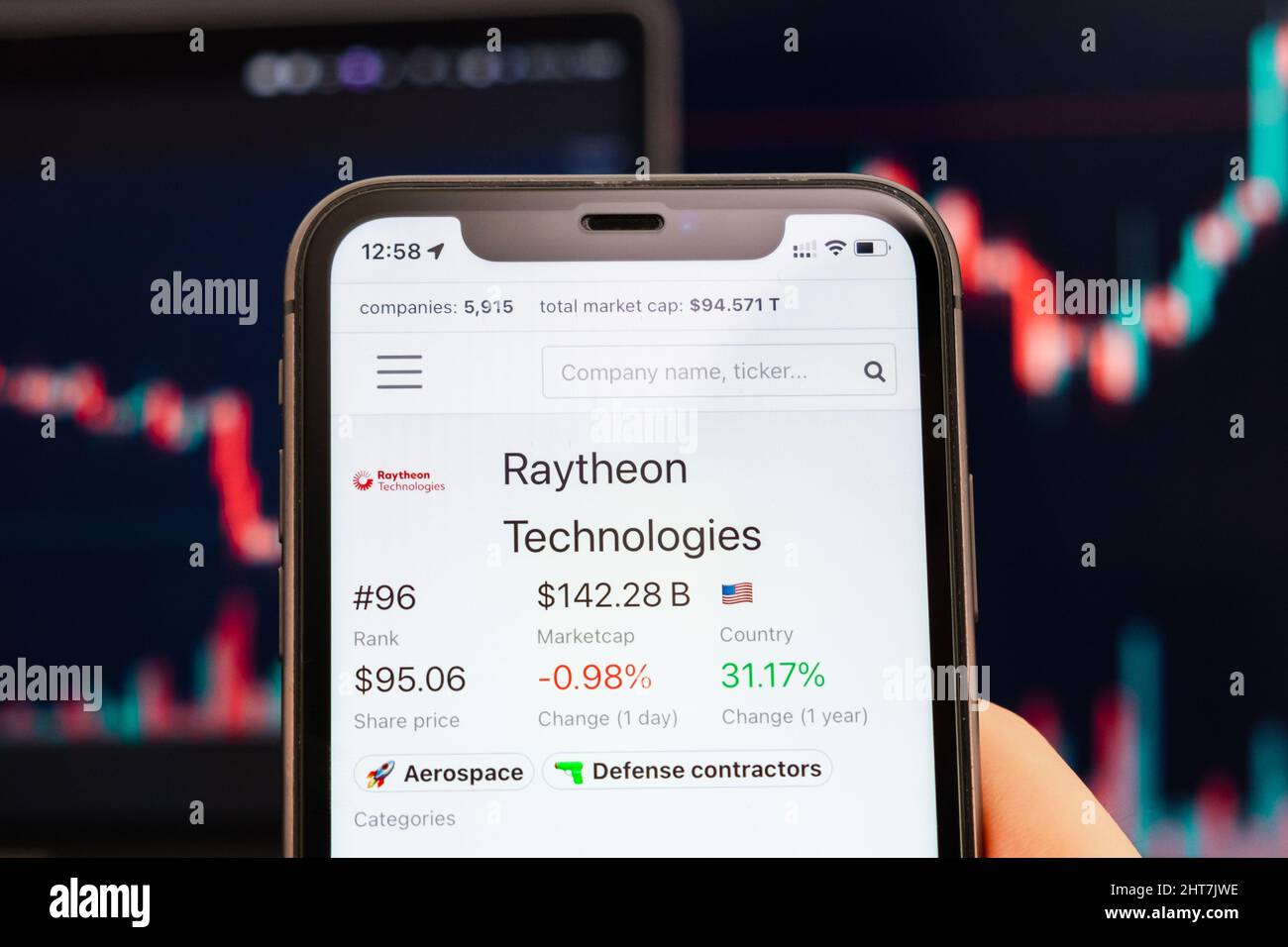Raytheon Technologies stock price on the screen of cell phone in mans hand with changing stock market exchange with trading candlestick graph analysis, February 2022, San Francisco, USA Stock Photo