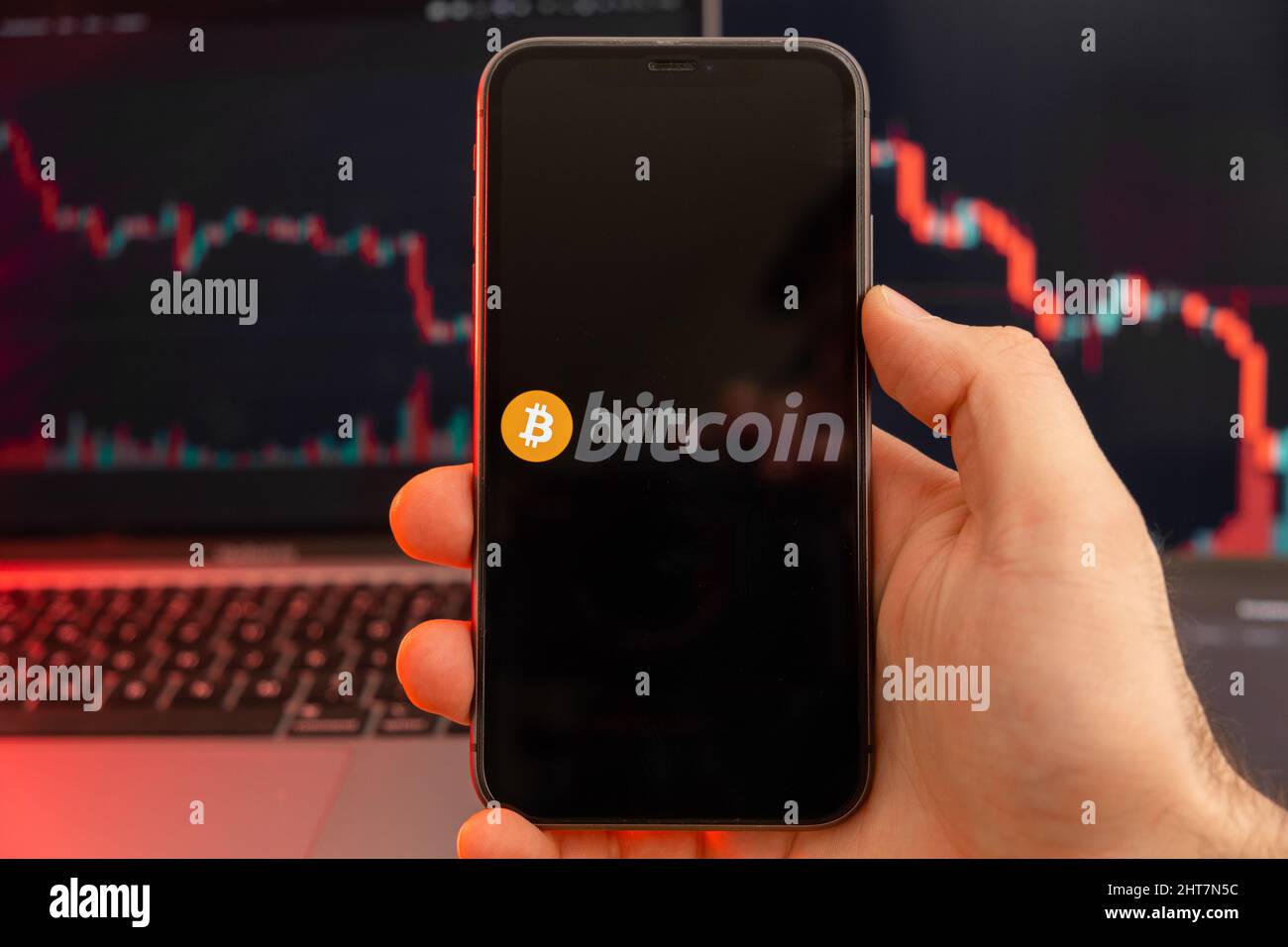 Bitcoin BTC app of cryptocurrency stock market analysis on the screen of mobile phone in man hands and downtrend charts trading data on the background, February 2022, San Francisco, USA. Stock Photo