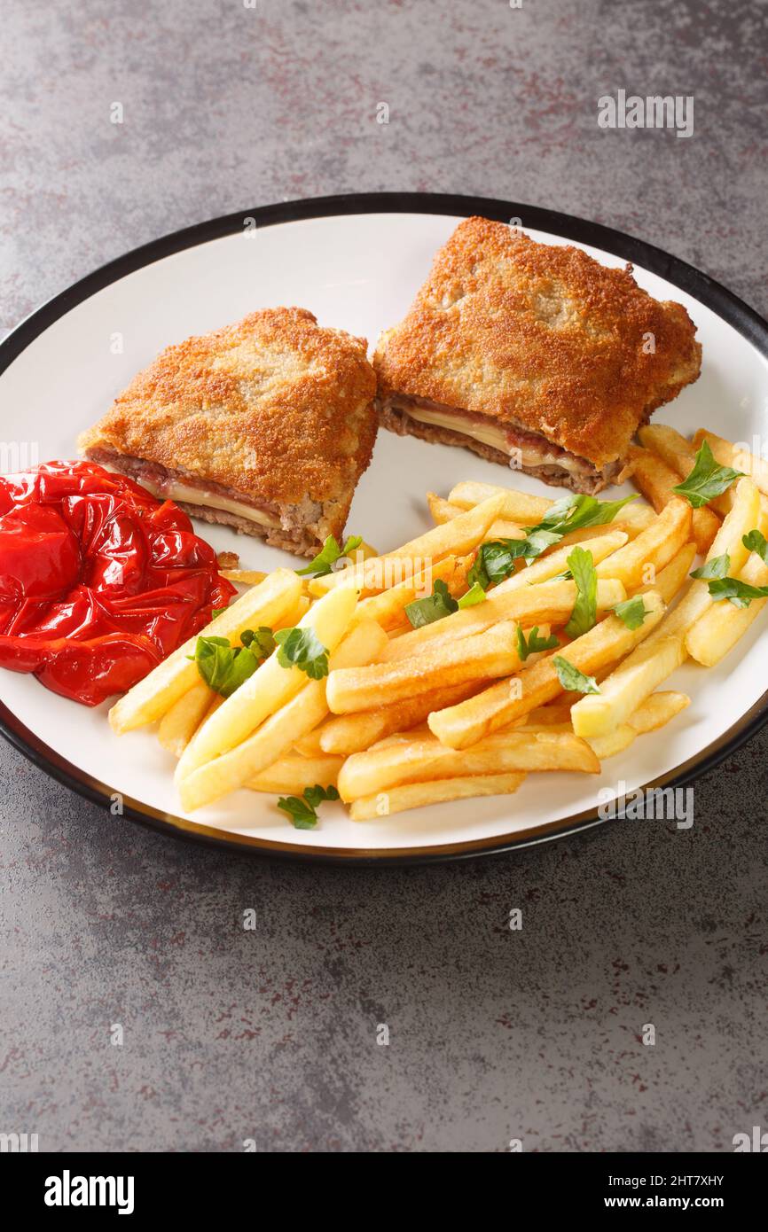 Breaded spanish steak Cachopo served with french fries close-up in a plate on the table. vertical Stock Photo