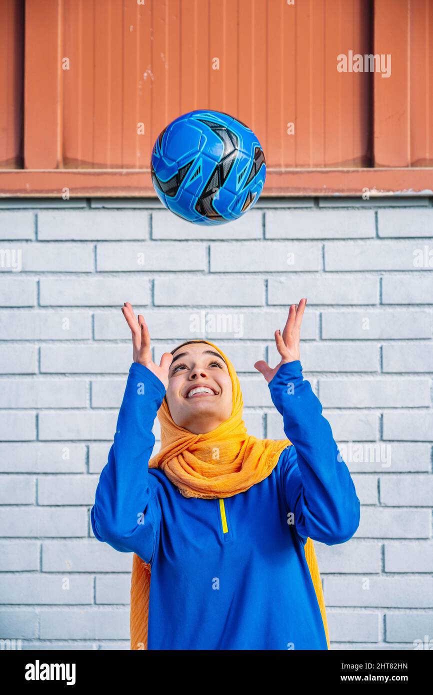 Smiling ethnic woman throwing football ball Stock Photo