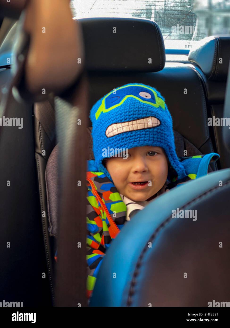 a child in a car seat in a car in a strange hat Stock Photo Alamy