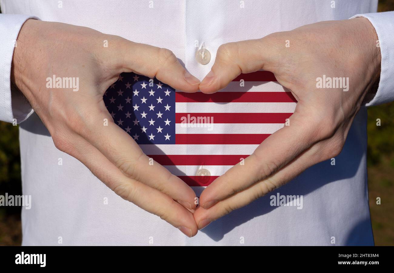 man holidng his hands in heart shaped on white shirt with usa flag colors national holiday concept . Stock Photo